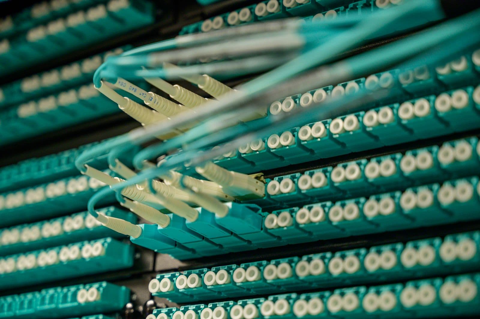 Glasfaserkabel, die an Netzwerktechnik angeschlossen sind. Ein VPN fügt einen Umweg und Verschlüsselung hinzu, sodass die Entfernung zum Server der mit Abstand größte Faktor dafür ist, wie stark es Sie verlangsamt.